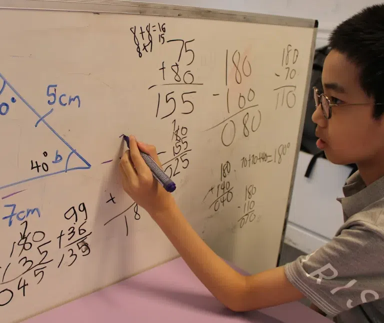 Student solving math equations on whiteboard